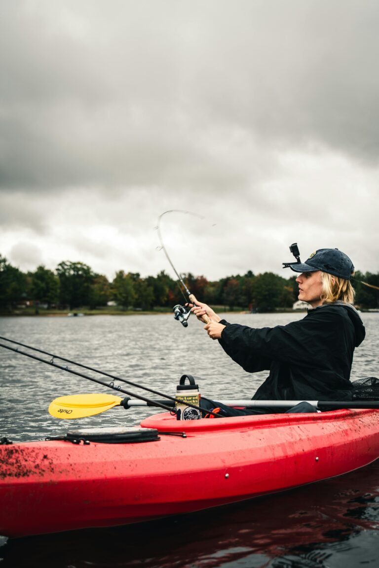 A woman in a kayak fishing on a lake under a cloudy sky, showcasing adventure.